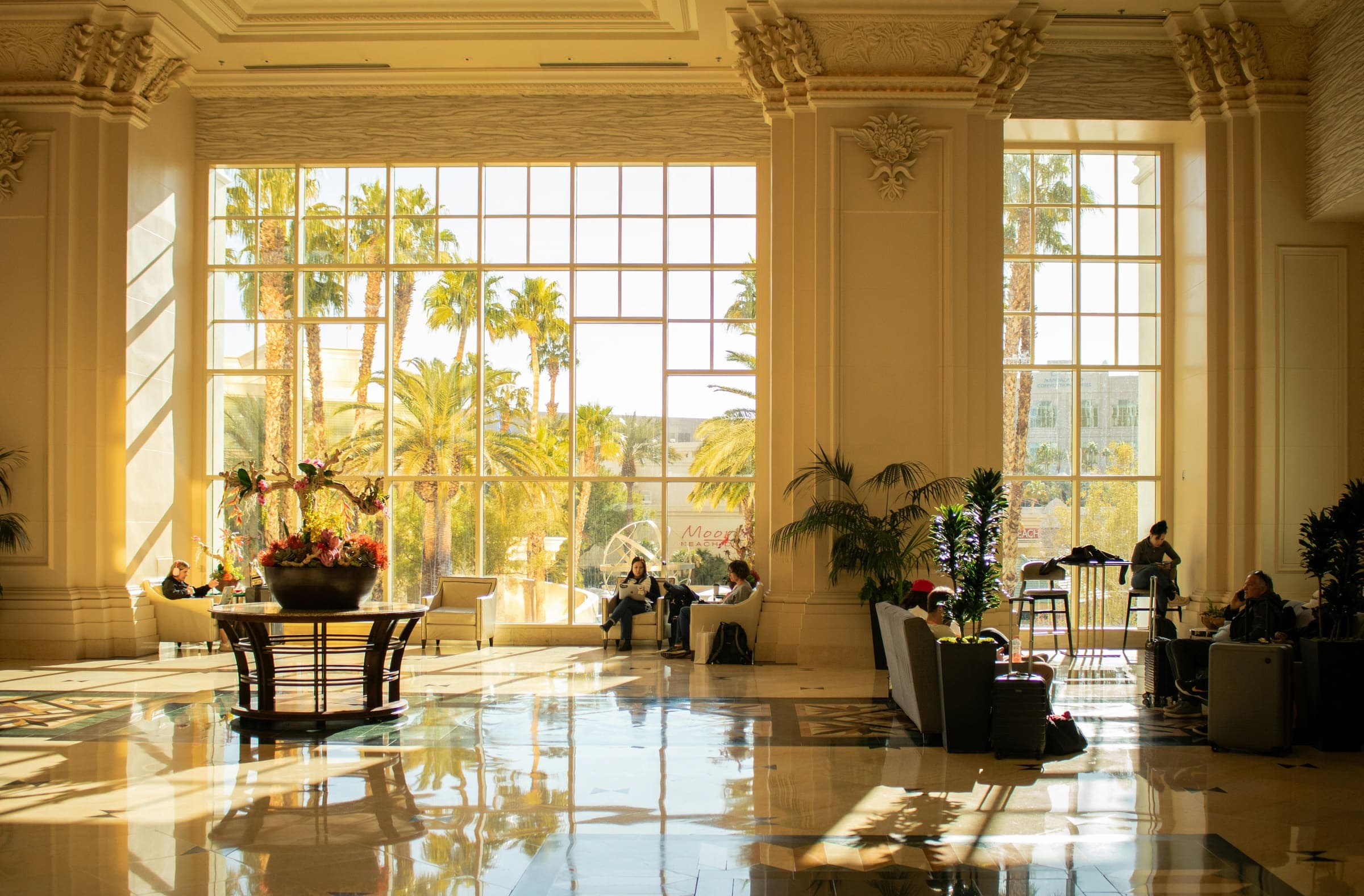 Le hall lumineux d'un hôtel de prestige ouvert sur un jardin de palmiers